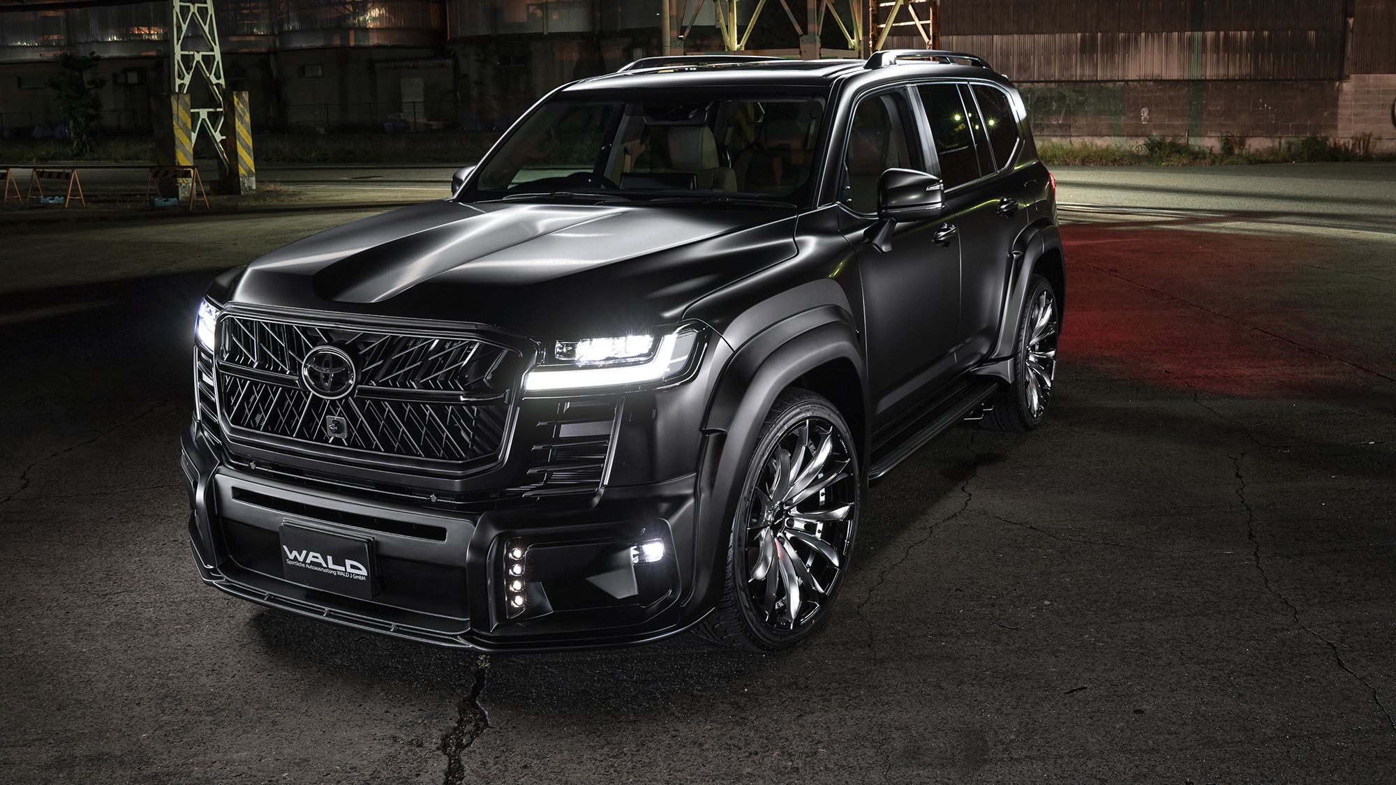 Matte black Wald-styled Toyota Land Cruiser with widebody aero kit and forged wheels at night